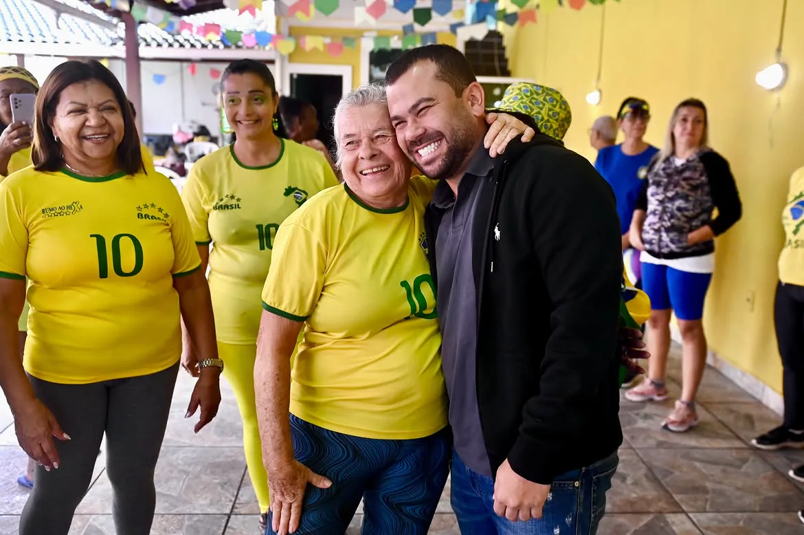 Felipe Pampolha abraçado a uma senhora de camisa da seleção brasileira, os dois sorrindo.